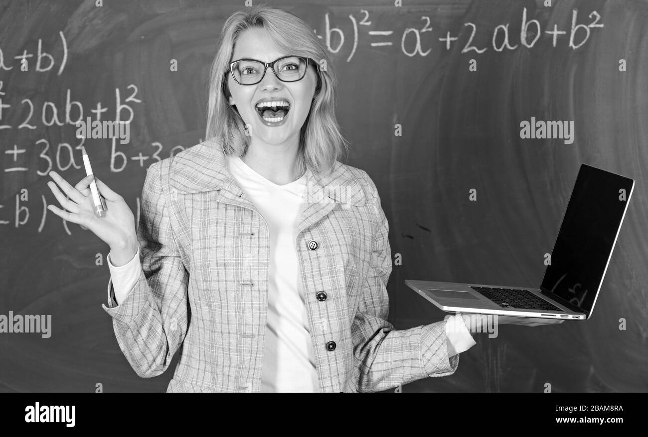 Enseignante portent des lunettes est titulaire d'ordinateur portable Internet surf. Les technologies numériques concept. Dame gaie éducateur avec ordinateur portable moderne tableau internet surf arrière-plan. L'éducation est amusant. Banque D'Images