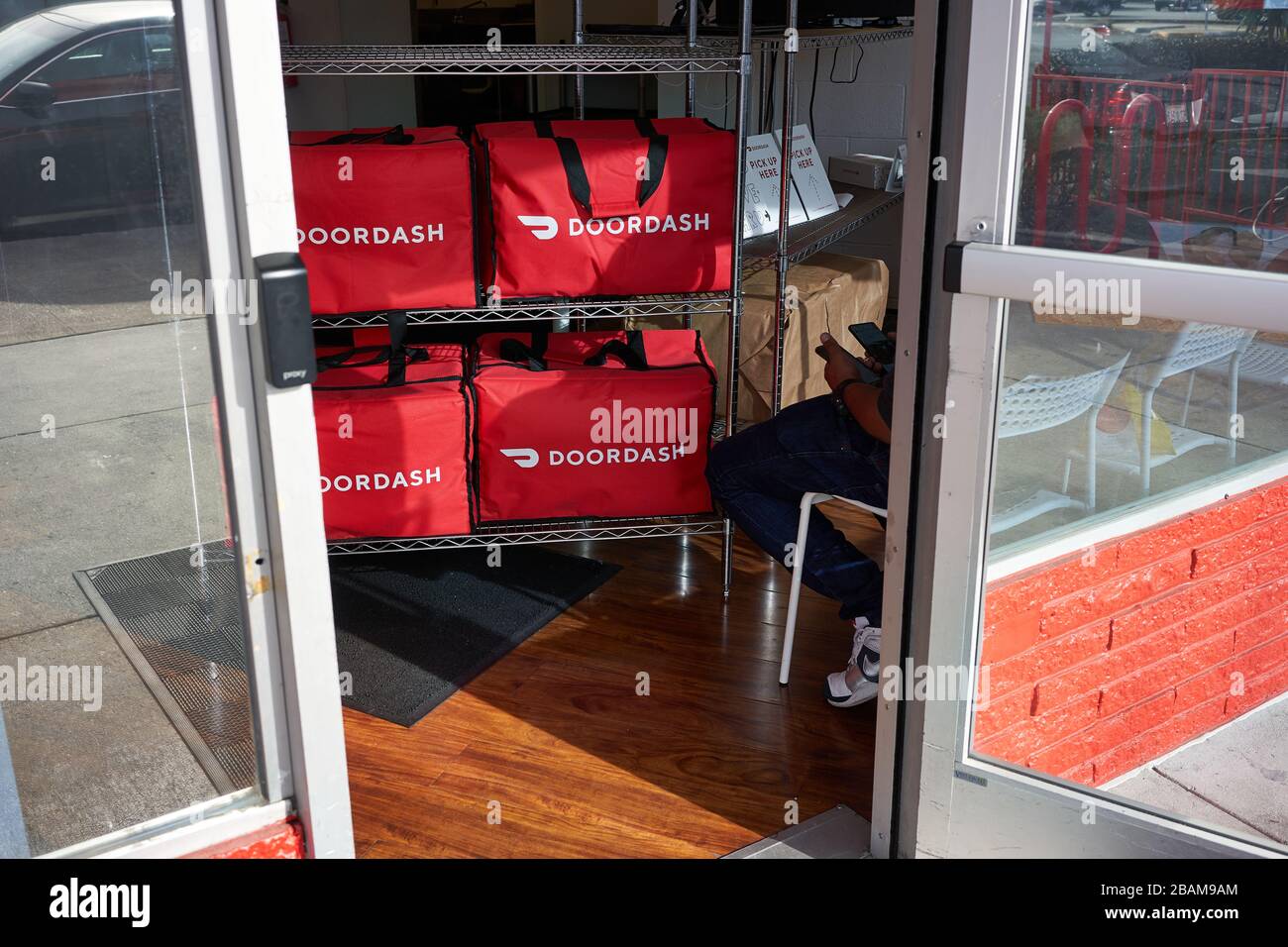 Un liveur de Doordash vérifie ses téléphones dans les cuisines de Doordash à Redwood City, en Californie. Banque D'Images