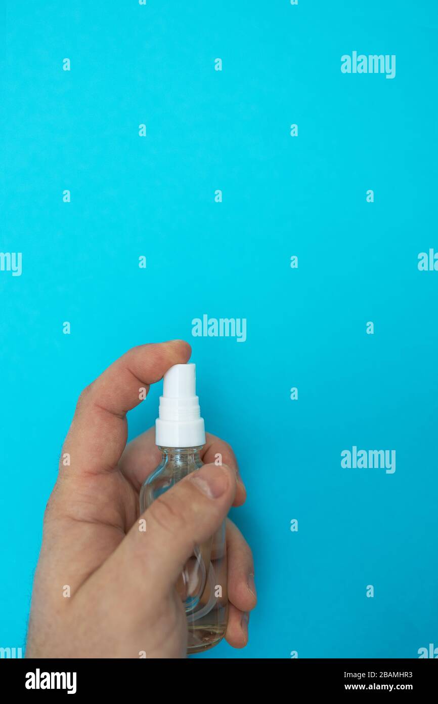 Mains avec désinfecteur antimagnétique sur fond bleu, vue du dessus, plat, espace de copie. Coronavirus pandémique dans le monde. Le concept d'arrêt du Banque D'Images
