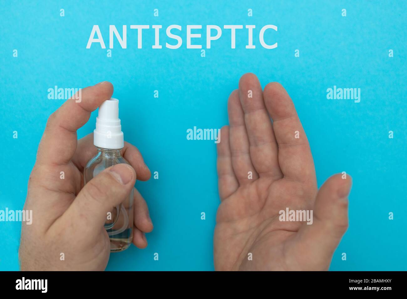 Mains avec désinfecteur ANTISEPTIQUE sur fond bleu et avec le texte ANTISEPTIQUE, vue de dessus, plat. Coronavirus pandémique dans le monde. Le concept de Banque D'Images