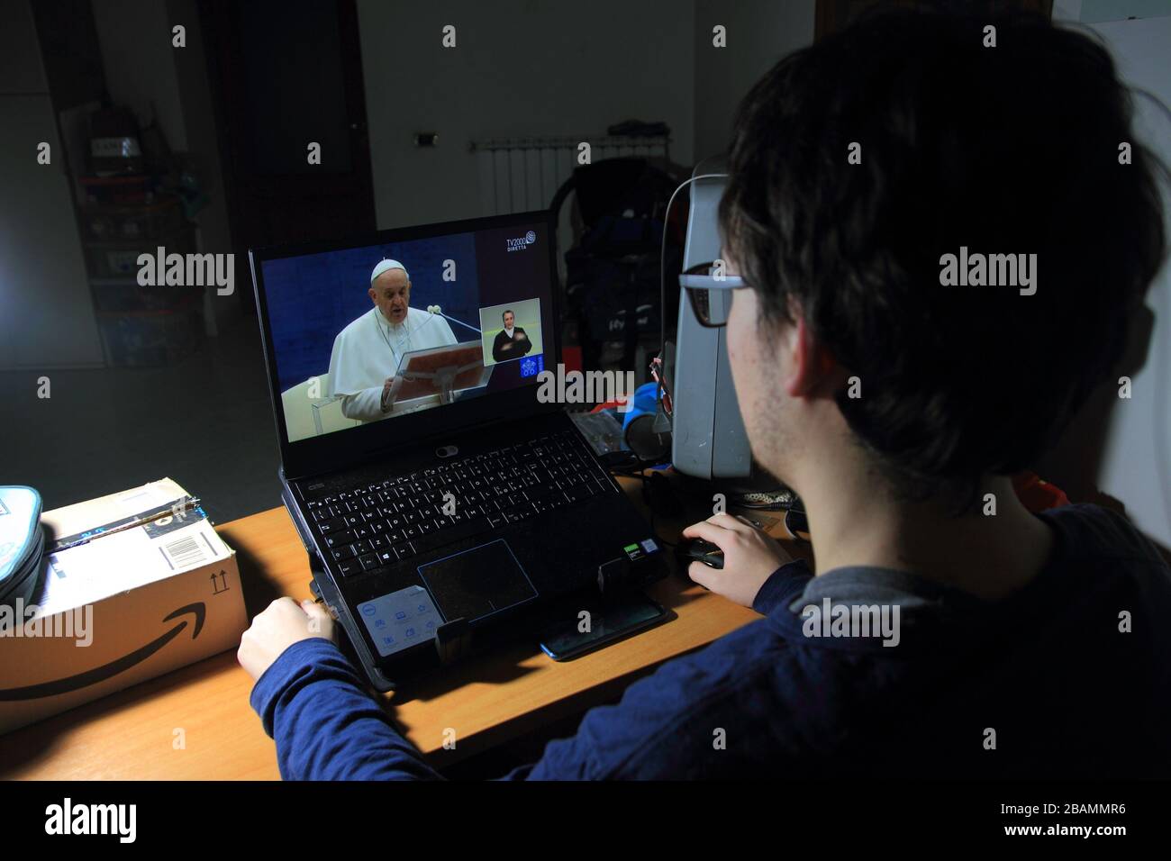 Pagani,sa,Italie-27 mars 2020:UN jeune étudiant est en streaming la télévision mondiale en direct du pape François sur son ordinateur portable pour donner la bénédiction mondiale urbi et orbi à Banque D'Images