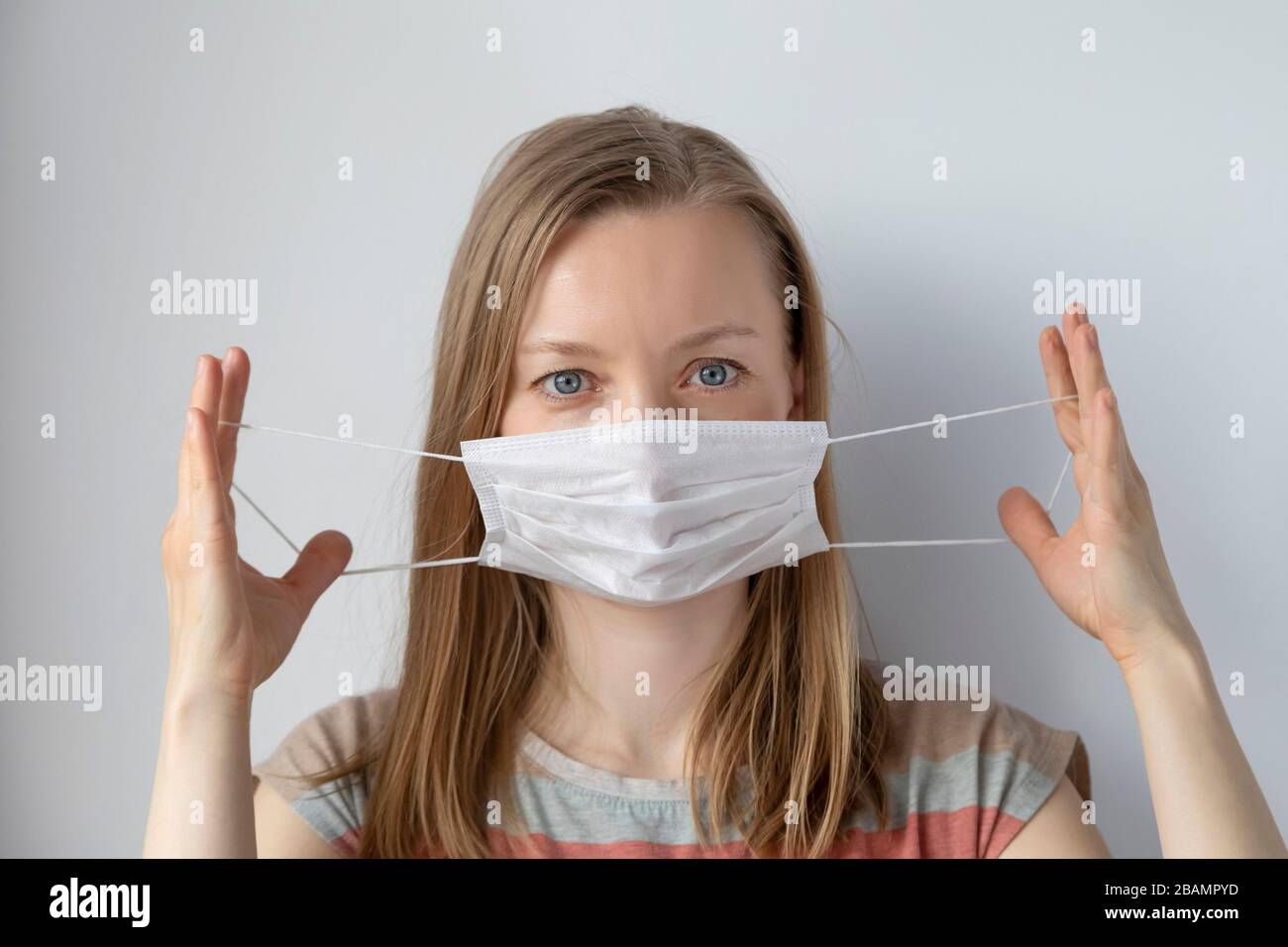 Une femme légère se met sur un masque médical pour la protection contre le virus Banque D'Images