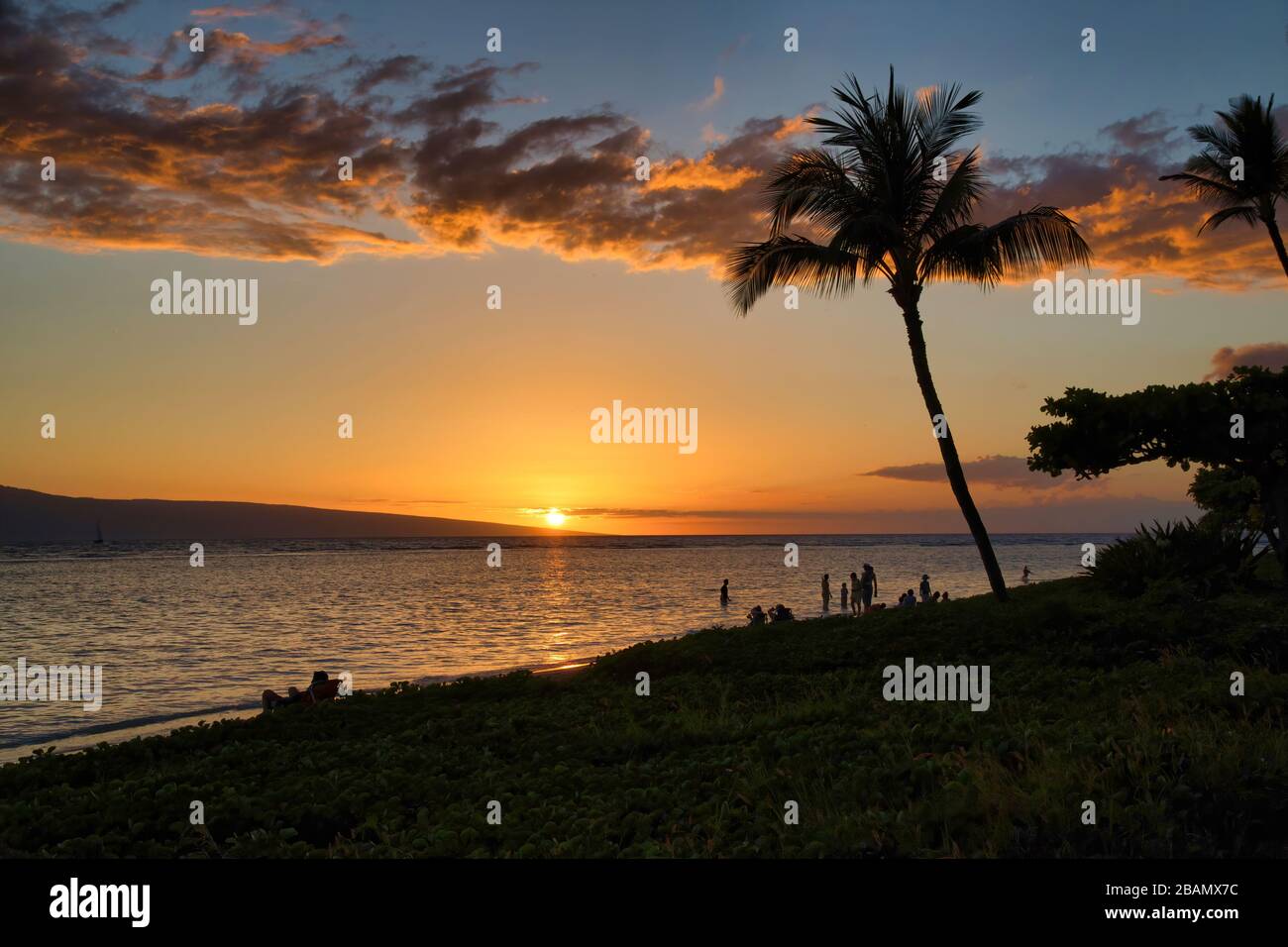 Baby Beach sur Maui au coucher du soleil avec Lanai en arrière-plan et palmier en premier plan. Banque D'Images