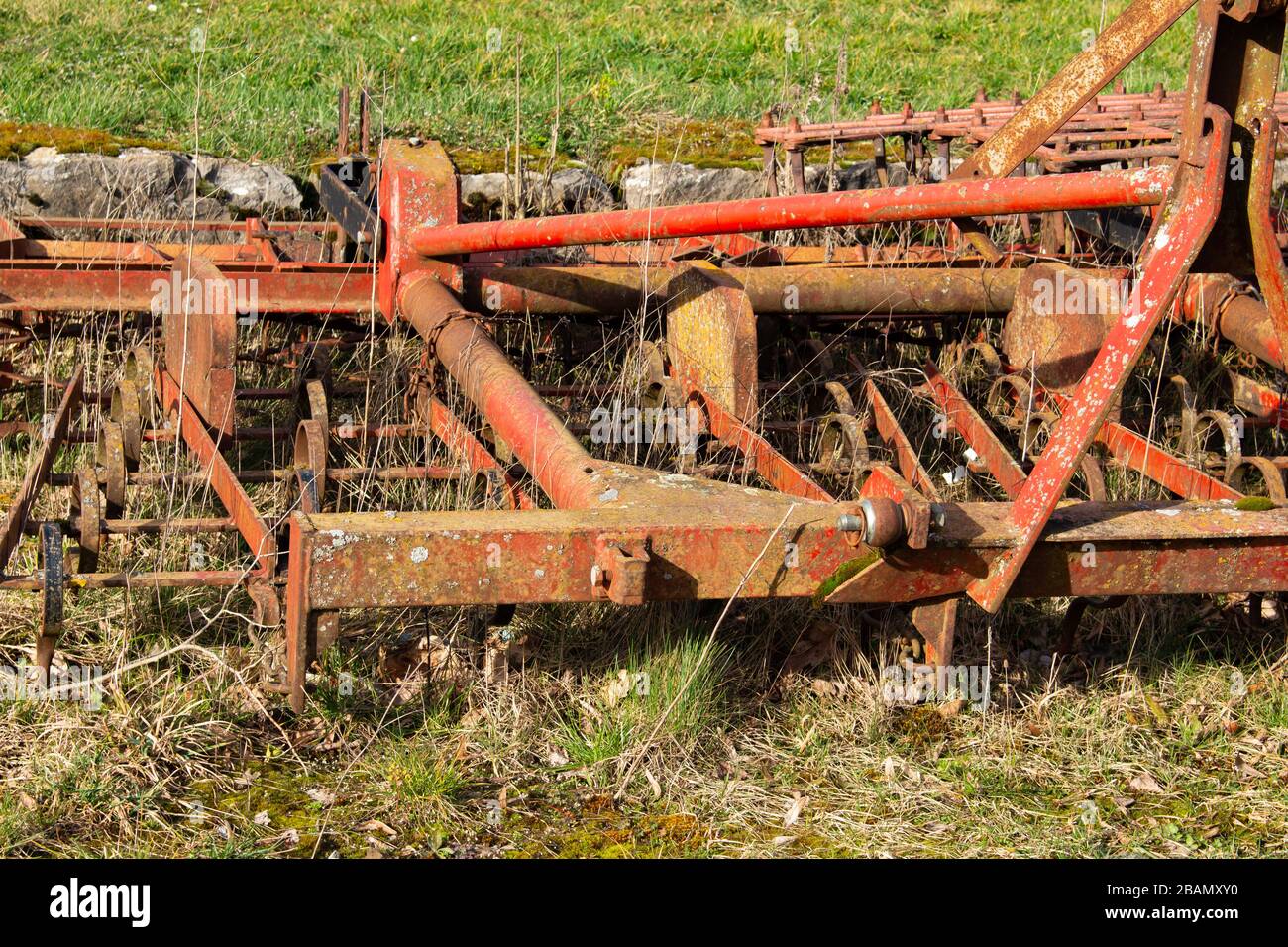 Gros plan sur un vieux cultivateur rouge et rouillé utilisé pour cultiver des terres agricoles Banque D'Images