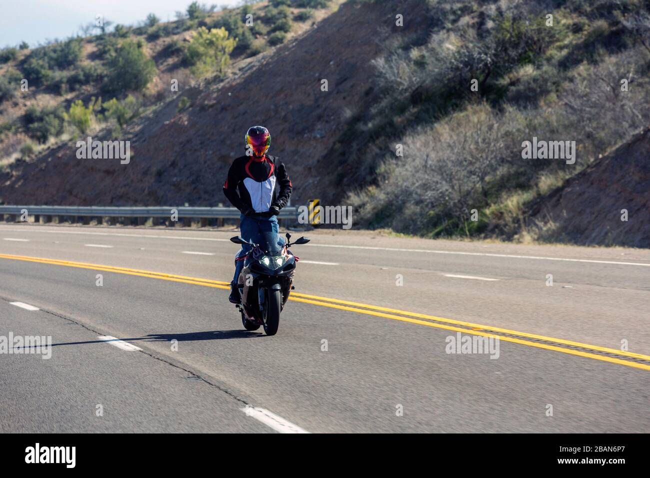 Moto pilote sur une route de montagne debout sur sa moto Photo Stock - Alamy