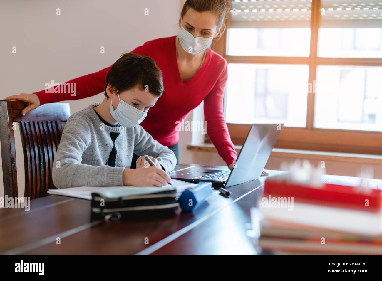 Mère et enfant ayant une séance d'apprentissage en ligne avec l'enseignant pendant la crise Banque D'Images