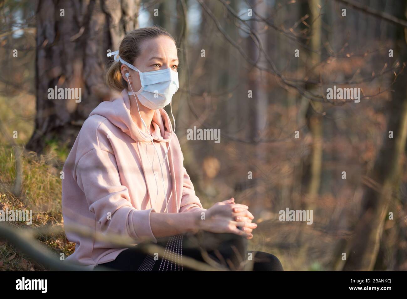 Portrait d'une femme sportive caucasienne portant un masque de protection médicale tout en se relaxant dans la nature et en écoutant de la musique. Le virus Corona, ou Covid-19, est Banque D'Images