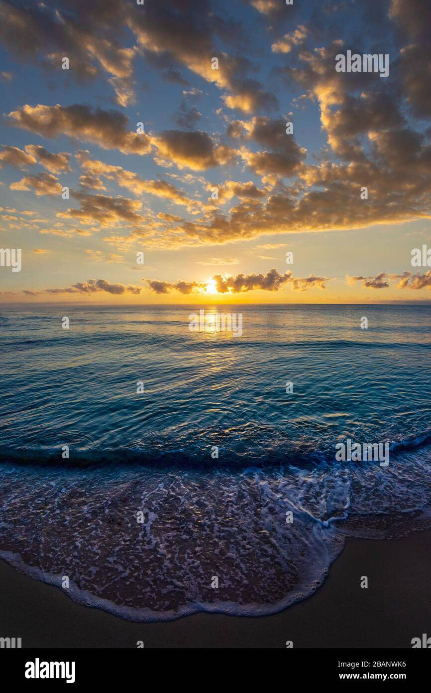 Magnifique paysage de nuages au lever du soleil sur la mer avec des vagues qui s'enroulent sur la plage de sable. Banque D'Images