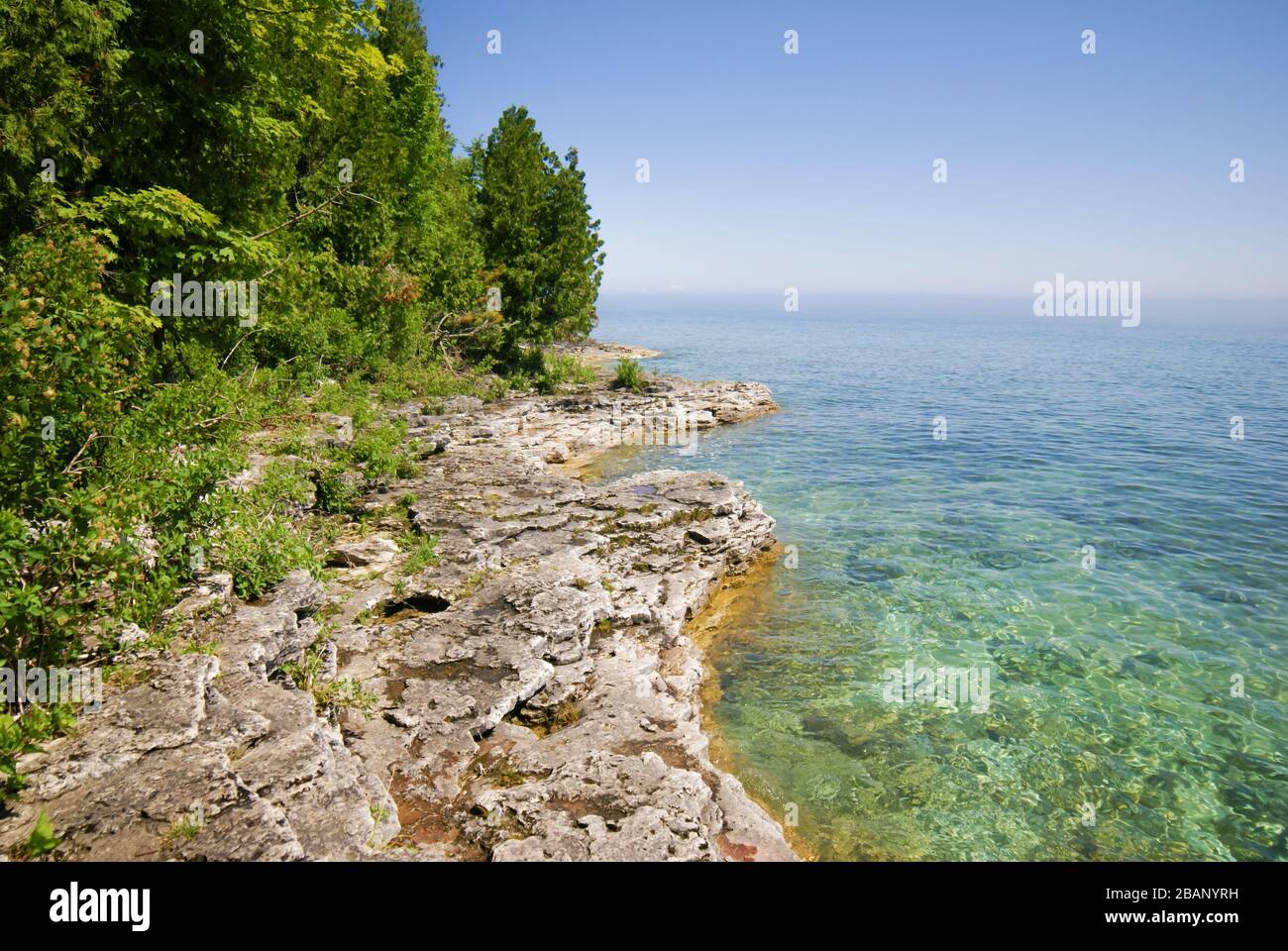 Lac bleu clair à droite, terrain rocheux gris avec des arbres verts à gauche dans Peninsula State Park dans Door County Wisconsin Banque D'Images