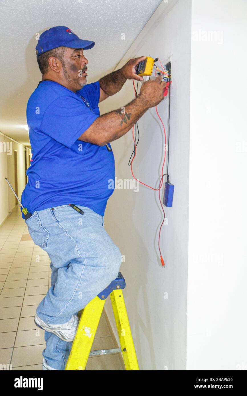 Miami Beach Florida,Presidential Condominiums,couloir,Black man hommes hommes adultes,alarme incendie,détecteur de fumée,installateur,technicien,réparateur,échelle, Banque D'Images