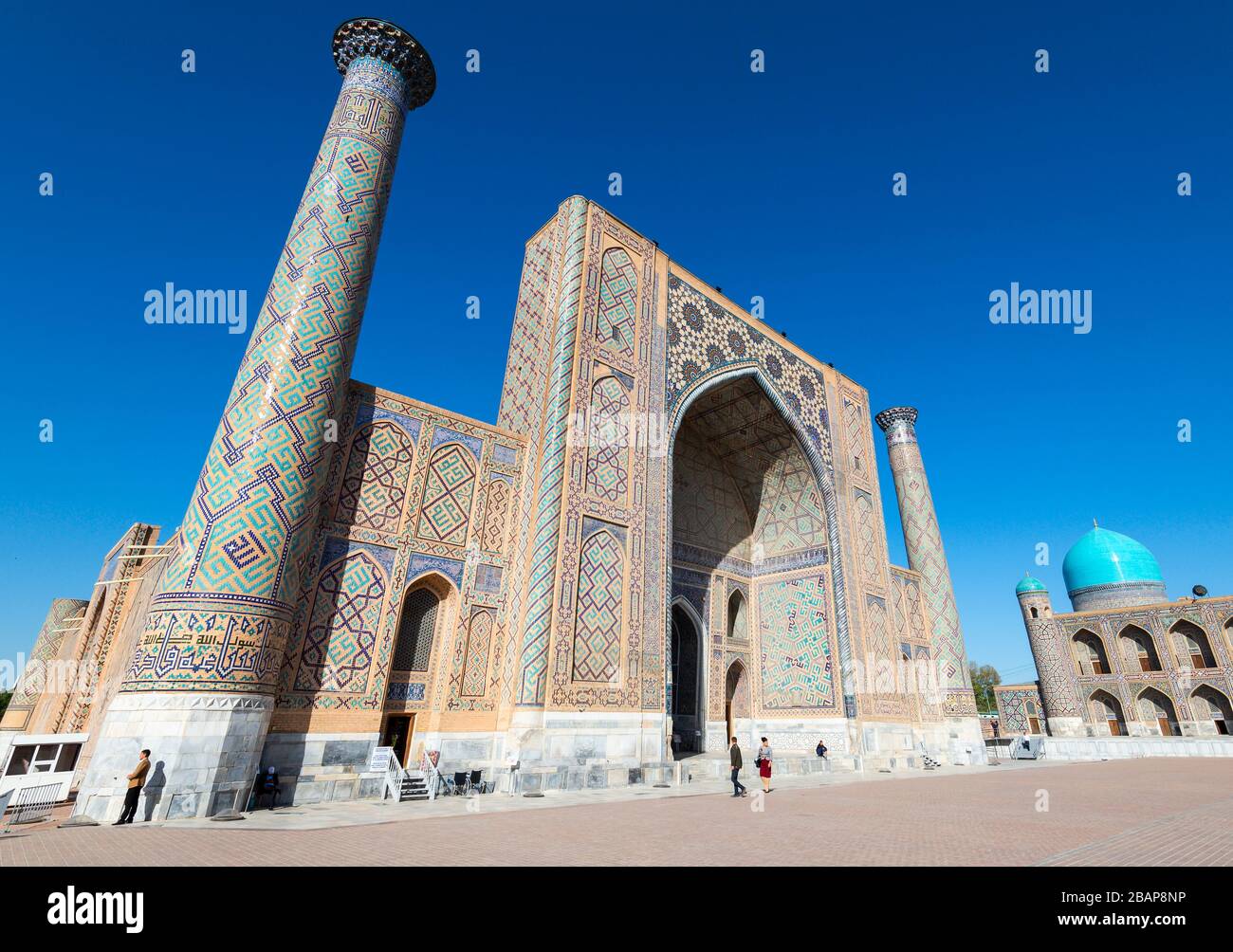Ulugh Beg Madrasah (école islamique) et ses deux minarets. Dôme bleu/turquoise de Tilya Kori Madrasa visible au Registan, Samarkand, Ouzbékistan. Banque D'Images