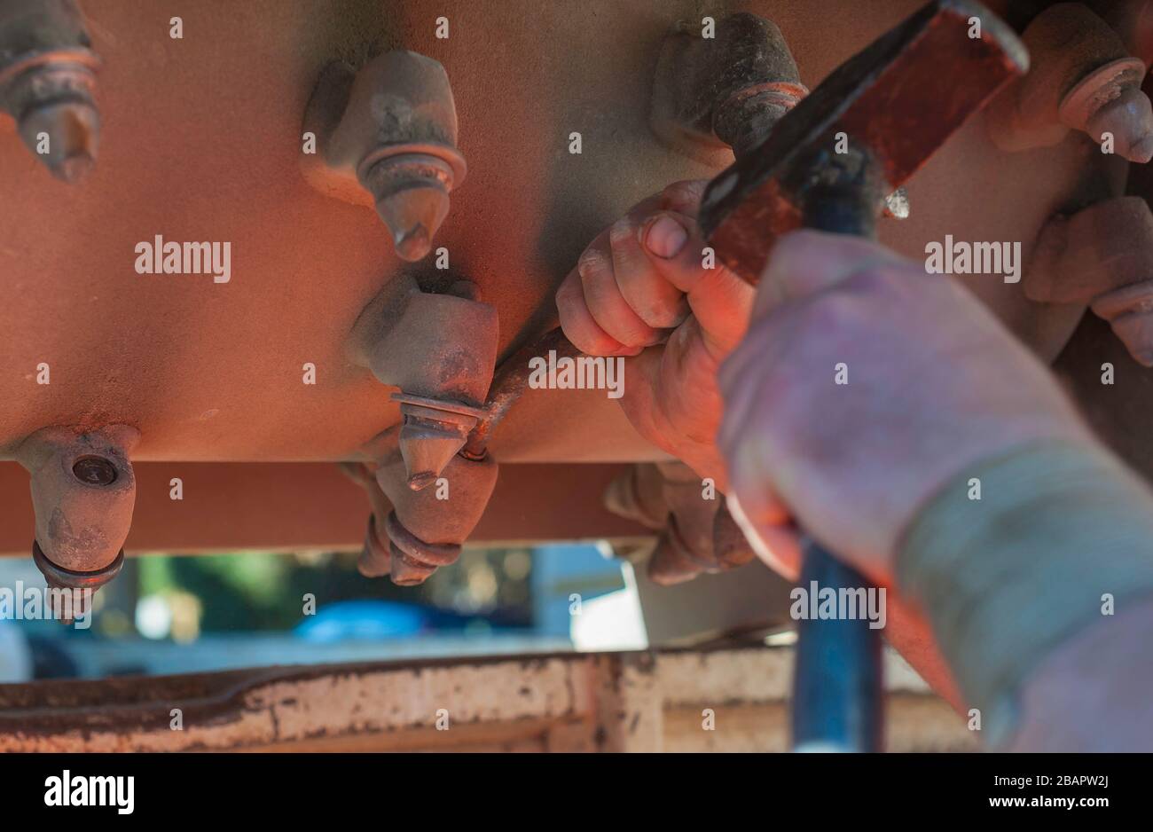 Le travailleur répare avec un marteau la couronne qui est montée sur une mini pelle hydraulique Banque D'Images