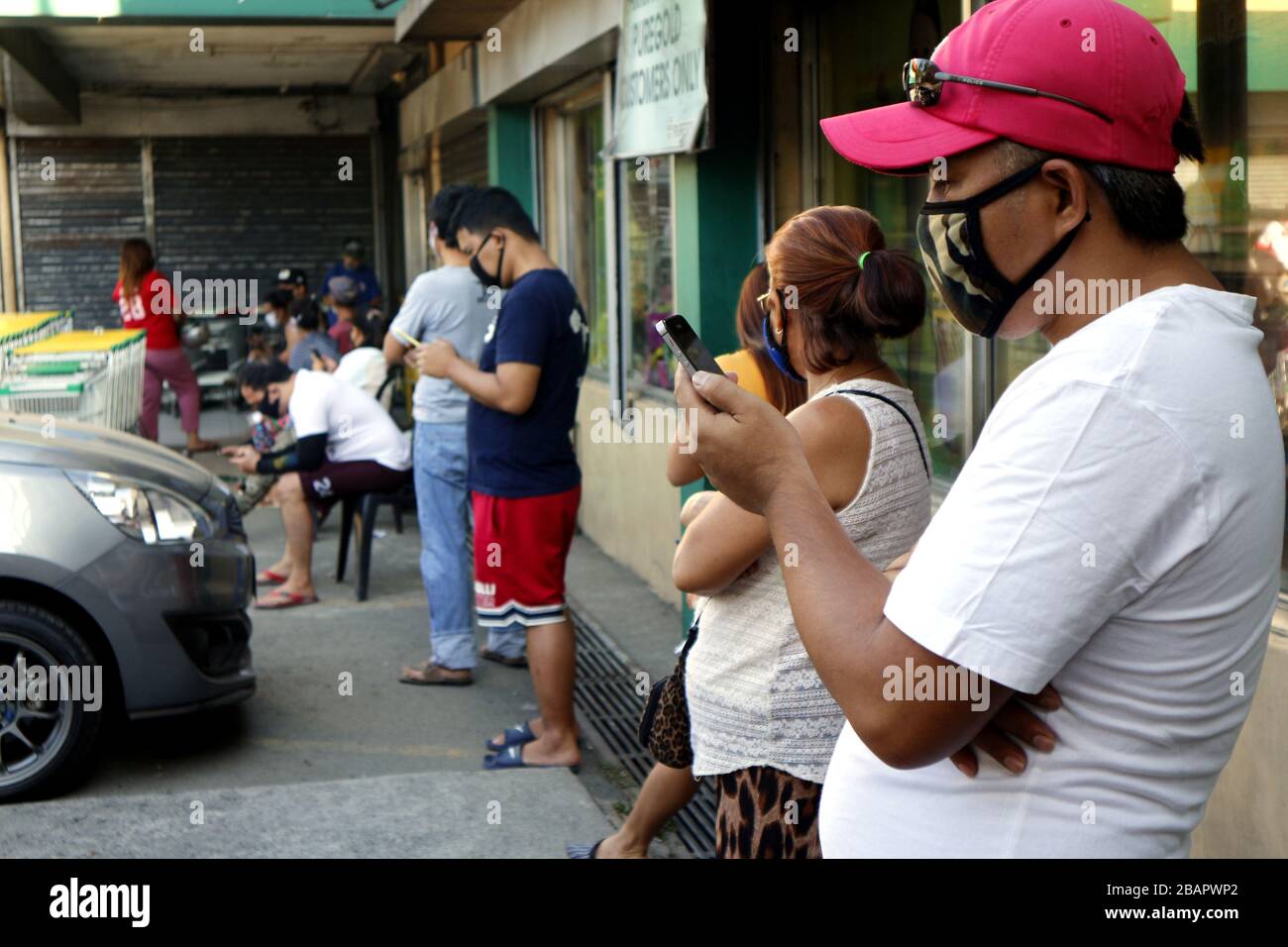 Antipolo City, Philippines - 26 mars 2020: Les clients se trouvent à l'extérieur d'une épicerie à distance l'un de l'autre pour distancer les réseaux sociaux pendant le Banque D'Images