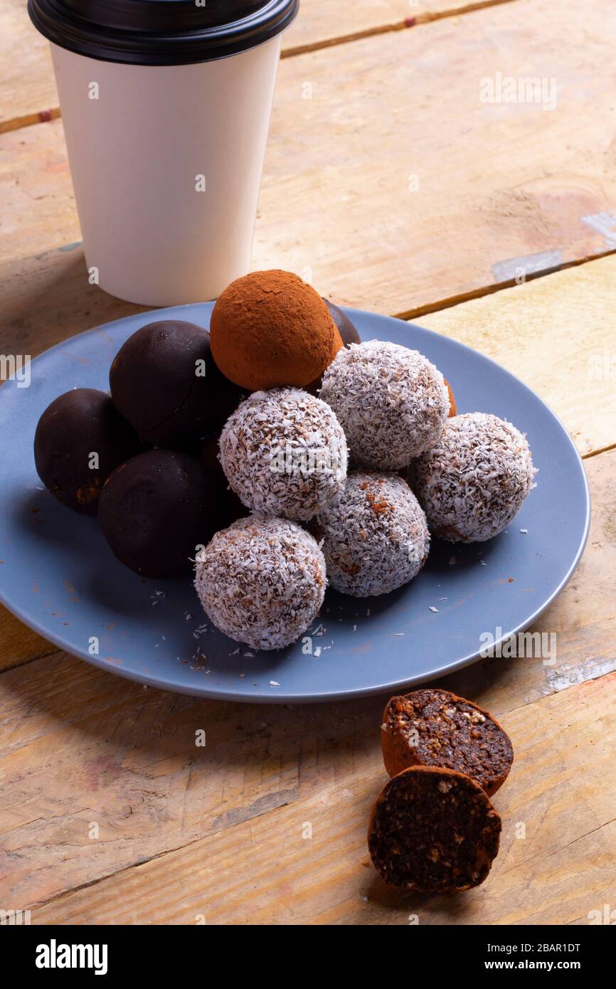 Boules bio d'énergie saine avec graines de sésame, noix de coco et une tasse de café Banque D'Images