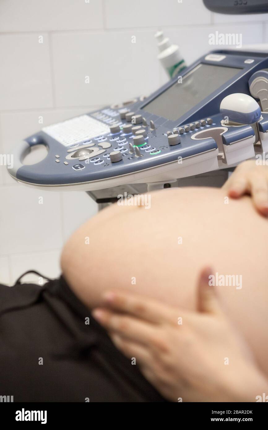 Ventre de la femme enceinte avec appareil d'échographie en arrière-plan, la  femme tenant le ventre avec les mains dessus Photo Stock - Alamy
