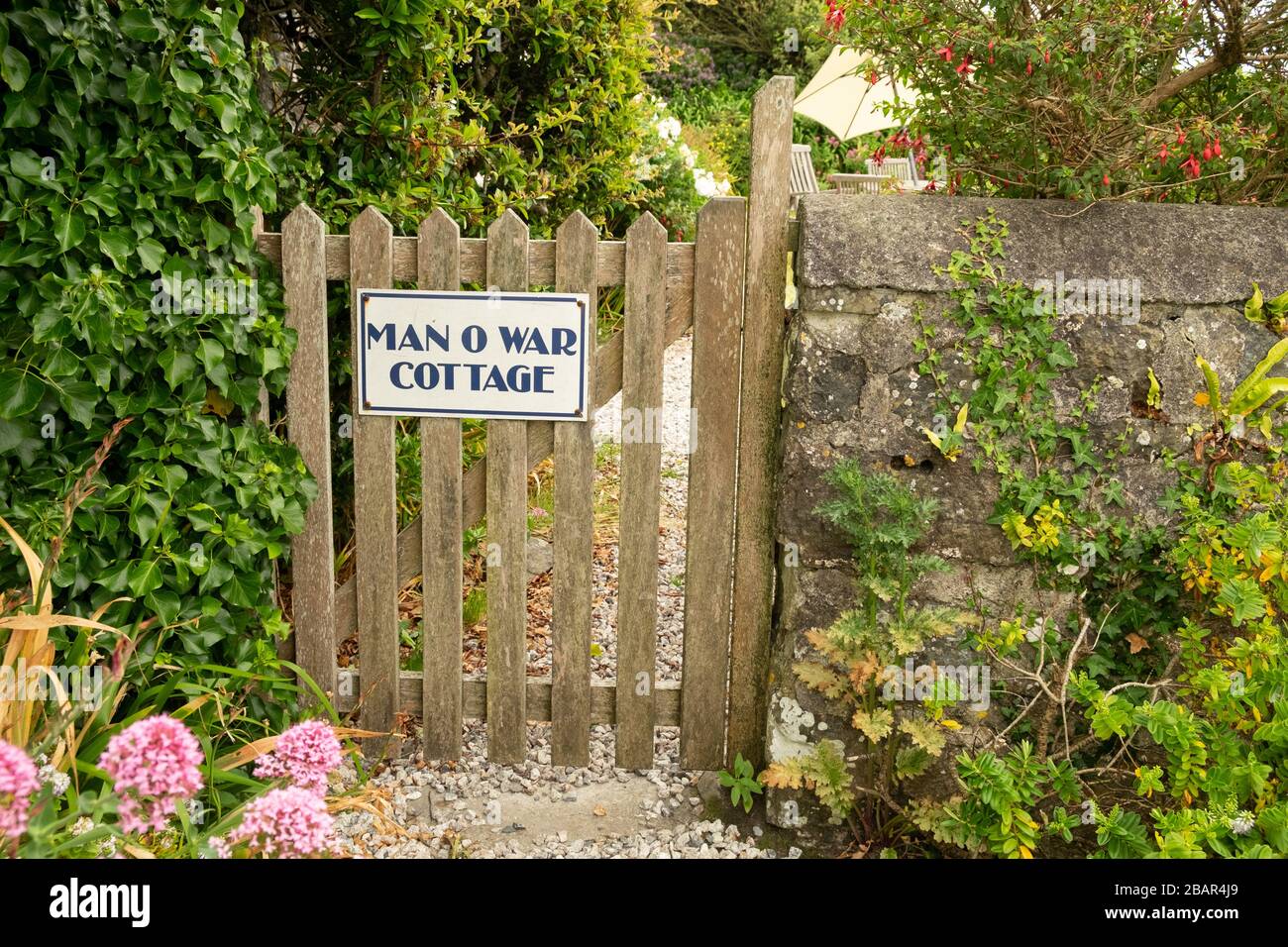 Porte de jardin en bois vers le cottage « Manan o War Cottage » et mur de pierre dans le petit village de pêcheurs pittoresque de Cadgwith, Cornwall, Angleterre Banque D'Images