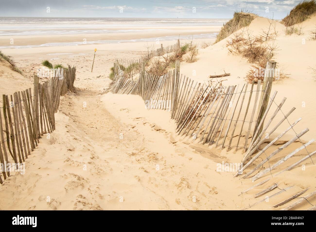 Chemin de sable avec clôtures en bois à grande plage et mer vides, Formby, Angleterre, Royaume-Uni Banque D'Images
