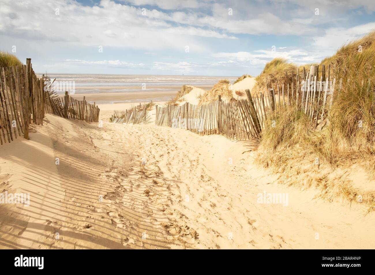 Chemin de sable avec clôtures en bois à grande plage et mer vides, Formby, Angleterre, Royaume-Uni Banque D'Images