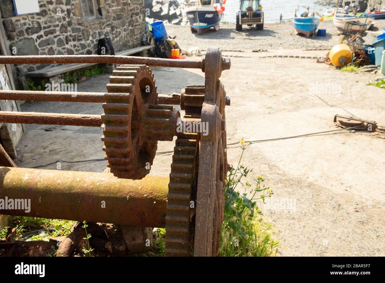 Vieux treuil déutilisé rouillé avec engrenage à crémaillère denté et câble utilisés pour treuil de pêche bateaux sur la plage dans le village de Cadgwith, Cornwall, Angleterre Banque D'Images