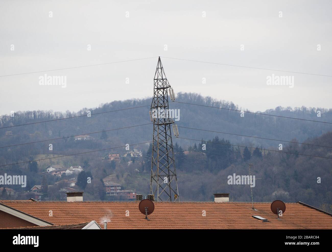 une tour de ligne de transmission haute tension électrique et des antennes satellites sur le toit Banque D'Images