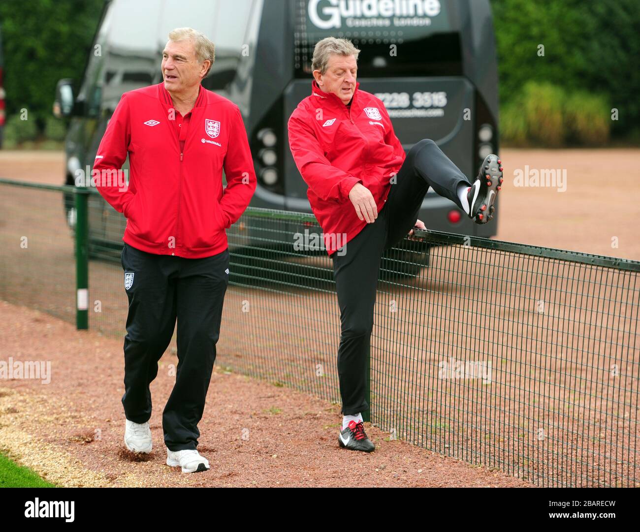Roy Hodgson, le directeur de l'Angleterre, monte sur une clôture avec Trevor Brooking sur leur chemin vers l'entraînement Banque D'Images