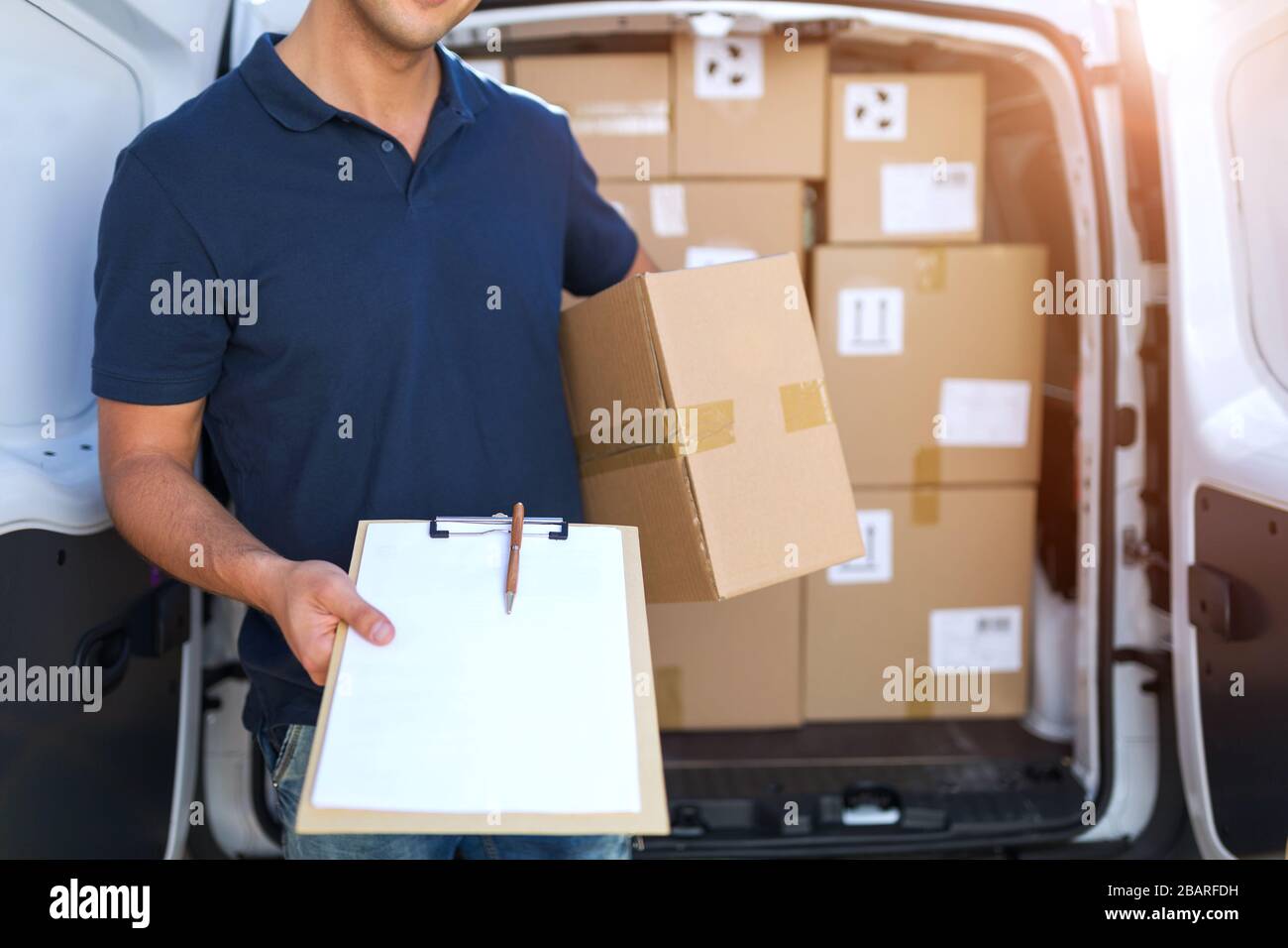 Homme souriant de livraison avec sa camionnette Banque D'Images