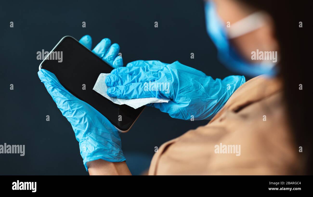 Femme en quarantaine portant des gants de protection téléphone de nettoyage Banque D'Images