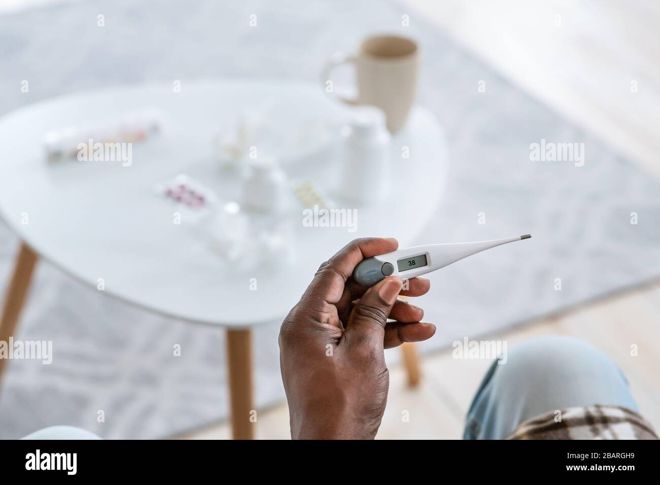 Traitement des maladies contagieuses. Homme d'Afrique senior avec thermomètre montrant la température de la fièvre à l'intérieur, gros plan Banque D'Images