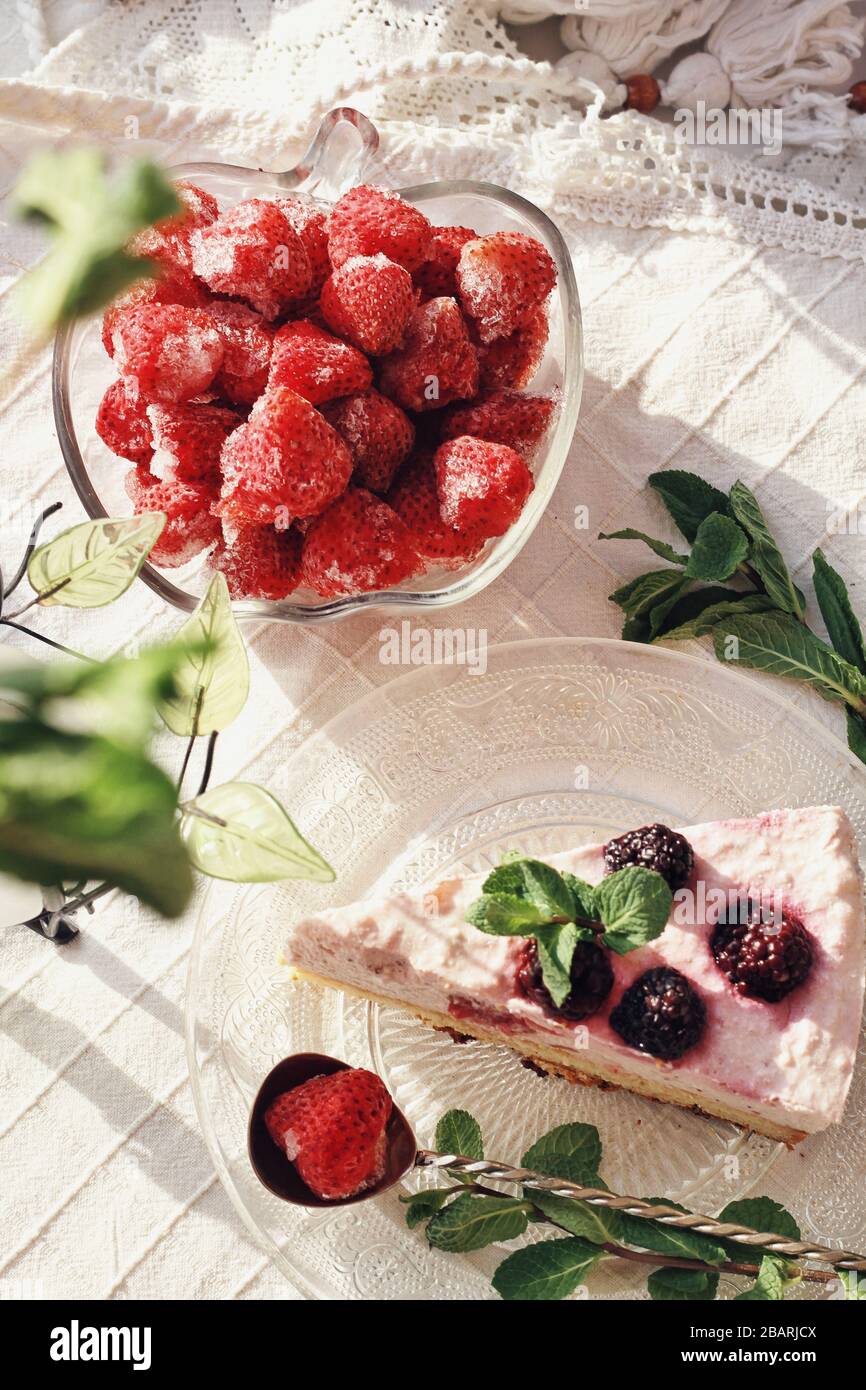 Le printemps est très agréable à la maison. Délicieux dessert frais avec baies et décoration verte, mets sucrés, thé. Délicieux gâteau et fraises sur la serviette blanche Banque D'Images