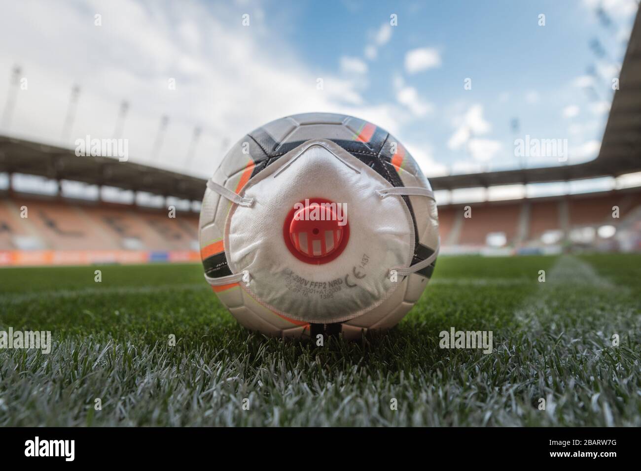 LUBIN, POLOGNE - 12 MARS 2020. Le ballon avec masque (symbole coronavirus) dans le coin du terrain de football. De nombreux événements sportifs ont été annulés à cause de Banque D'Images