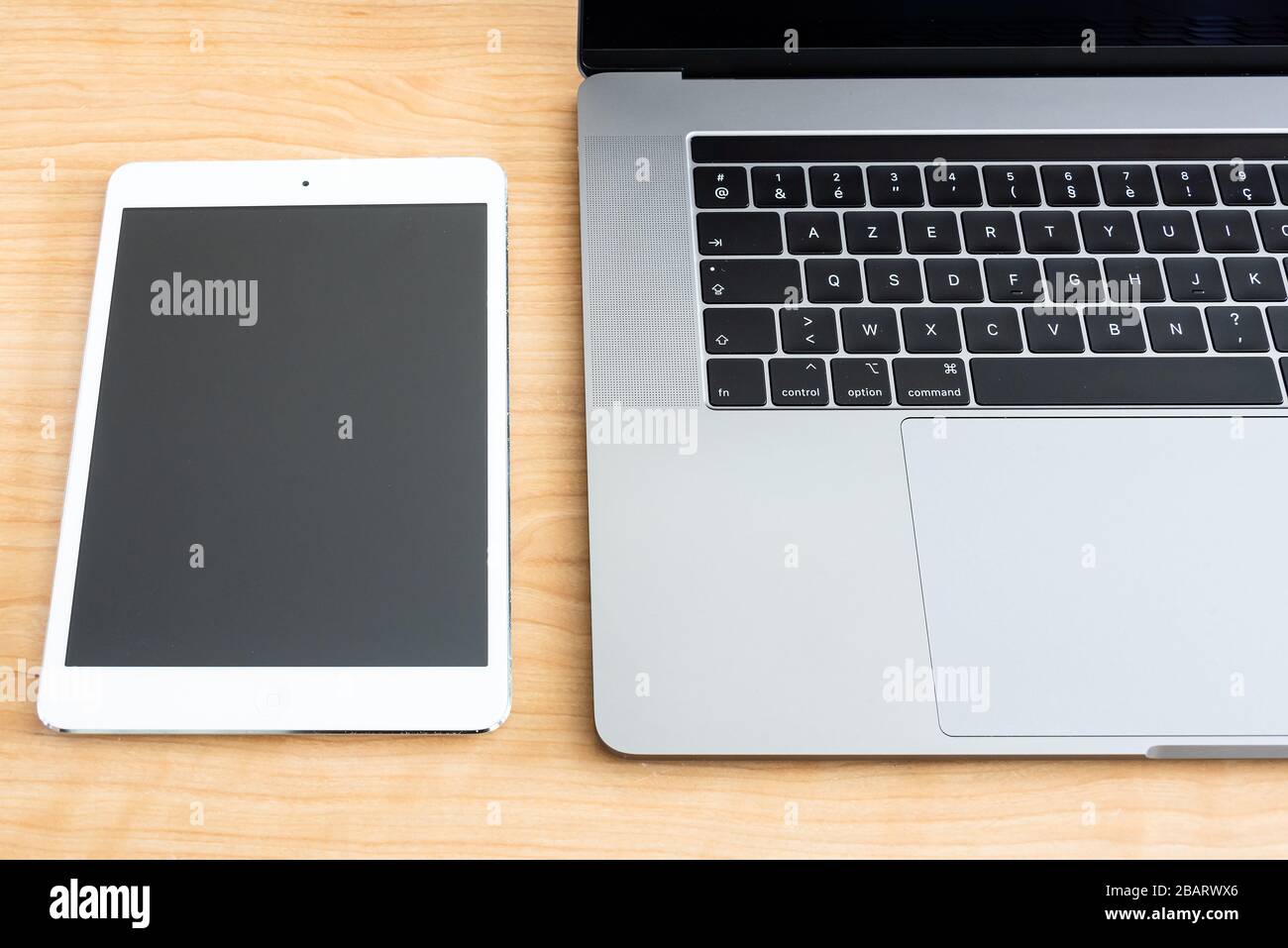 Une tablette blanche et un ordinateur portable sur une surface en bois. Banque D'Images