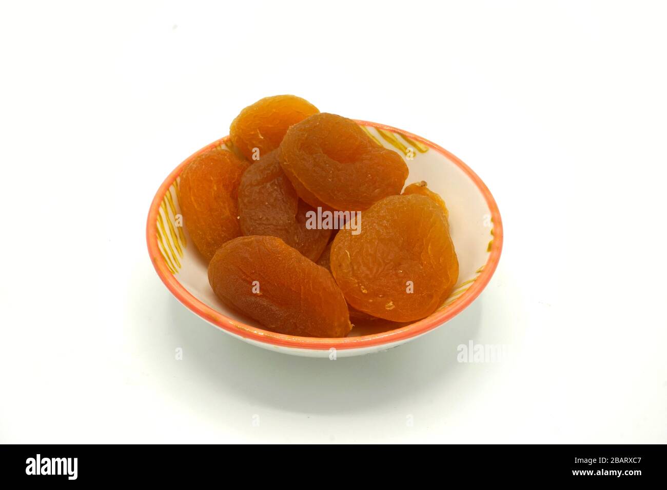 Abricots secs sur une soucoupe en céramique isolée sur fond blanc. Source naturelle d'énergie et de fibres. Banque D'Images