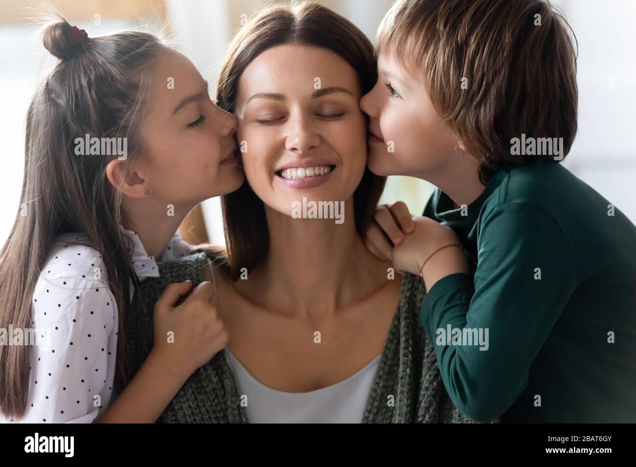 Petits enfants affectueux frères et sœurs embrassant les joues de jeune momie affectueuse. Banque D'Images