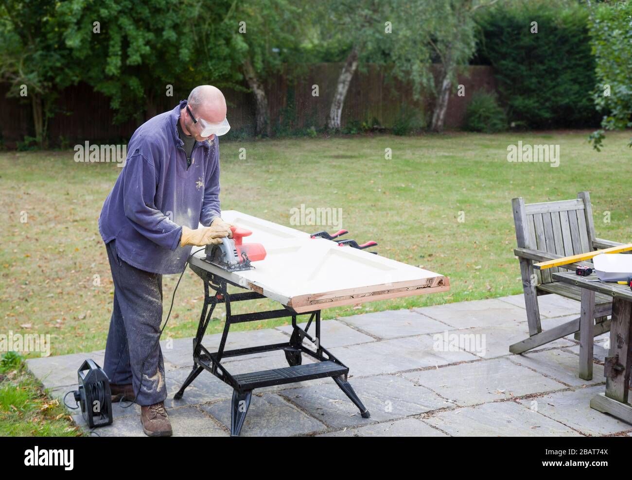 Bricolage menuiserie et amélioration de la maison, homme utilisant une scie circulaire pour redimensionner une porte en bois, Royaume-Uni Banque D'Images