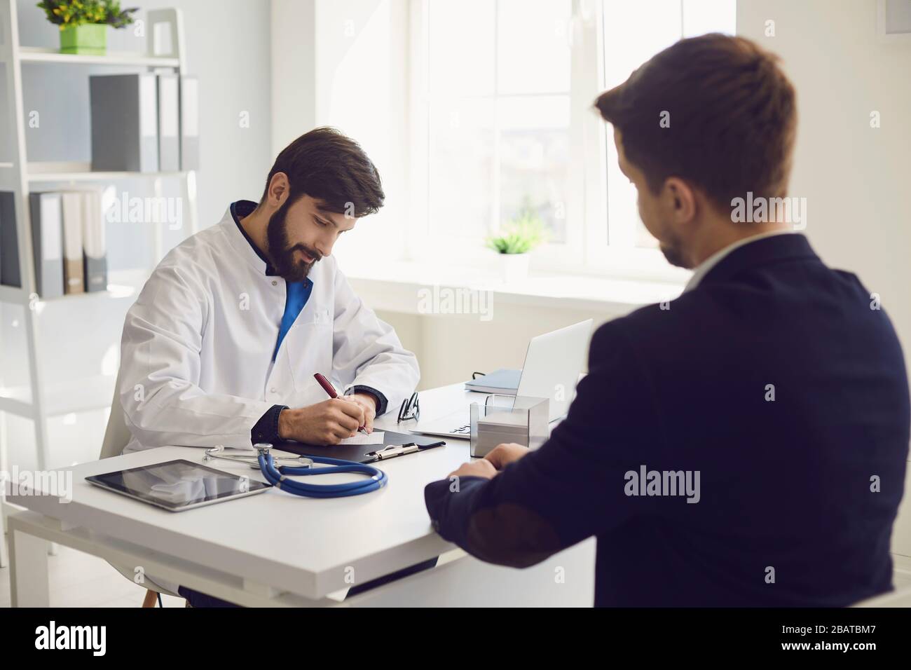 Médecin de visite du patient au bureau de la clinique. Le travail médical rédige une ordonnance sur une table dans un hôpital. Banque D'Images