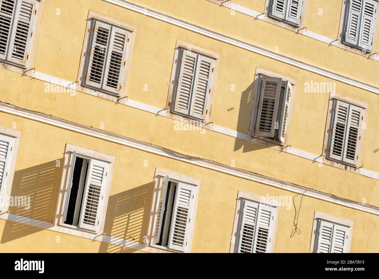 Bâtiment traditionnel de style méditerranéen avec volets blancs sur le mur jaune Banque D'Images