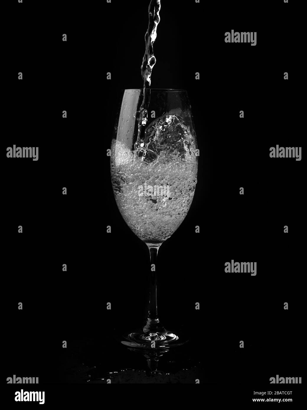 l'eau s'est éclabouée sur fond noir. Verser de l'eau dans du verre transparent sur fond noir. Banque D'Images