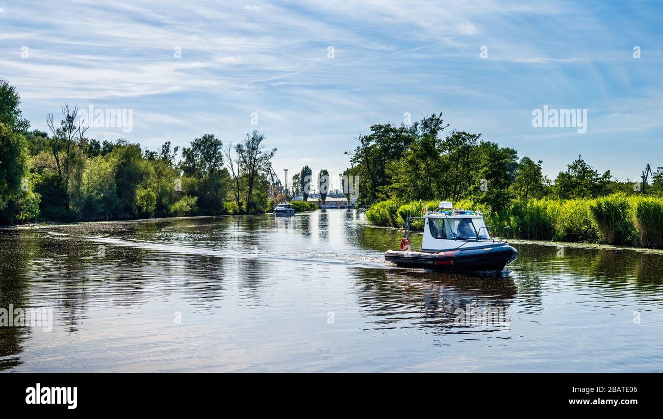 Le bateau gonflable à moteur flotte sur une rivière, entouré de roseaux et de tentatives, belle journée d'été sur la marina de bateaux de Szczecin, Pologne Banque D'Images
