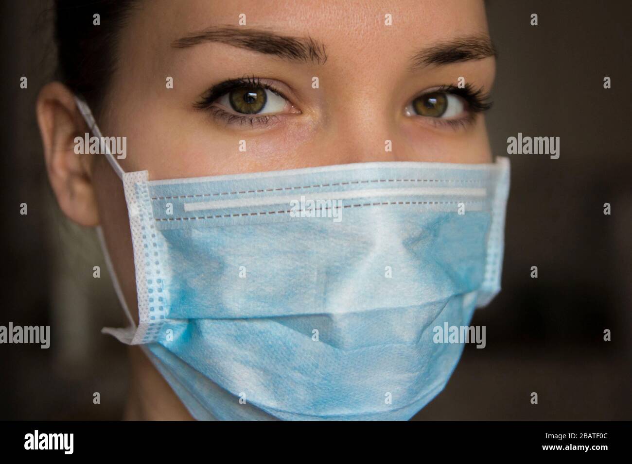 Femme portant un masque de protection contre le coronavirus sur fond sombre Banque D'Images Femme portant un masque de protection contre le coronavirus sur fond sombre Banque D'Images
