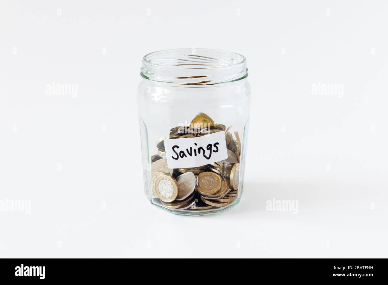 Un pot de confiture en verre contenant des pièces de monnaie britanniques, avec une étiquette manuscrite « avings » Banque D'Images