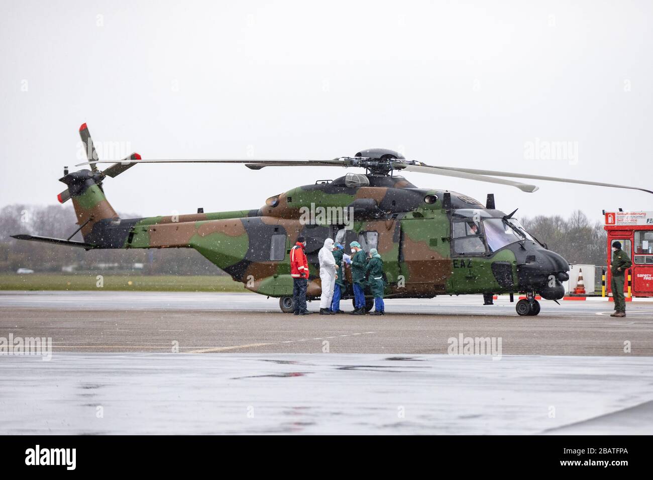 29 mars 2020, Rhénanie-du-Nord-Westphalie, Mülheim an der Ruhr: Les travailleurs de secours en vêtements de protection sortent d'un hélicoptère militaire français à l'aéroport. Auparavant, deux patients étaient amenés de Metz en France à Mühlheim pour être traités à l'hôpital universitaire d'Essen. Photo : Marcel Kusch/dpa Banque D'Images