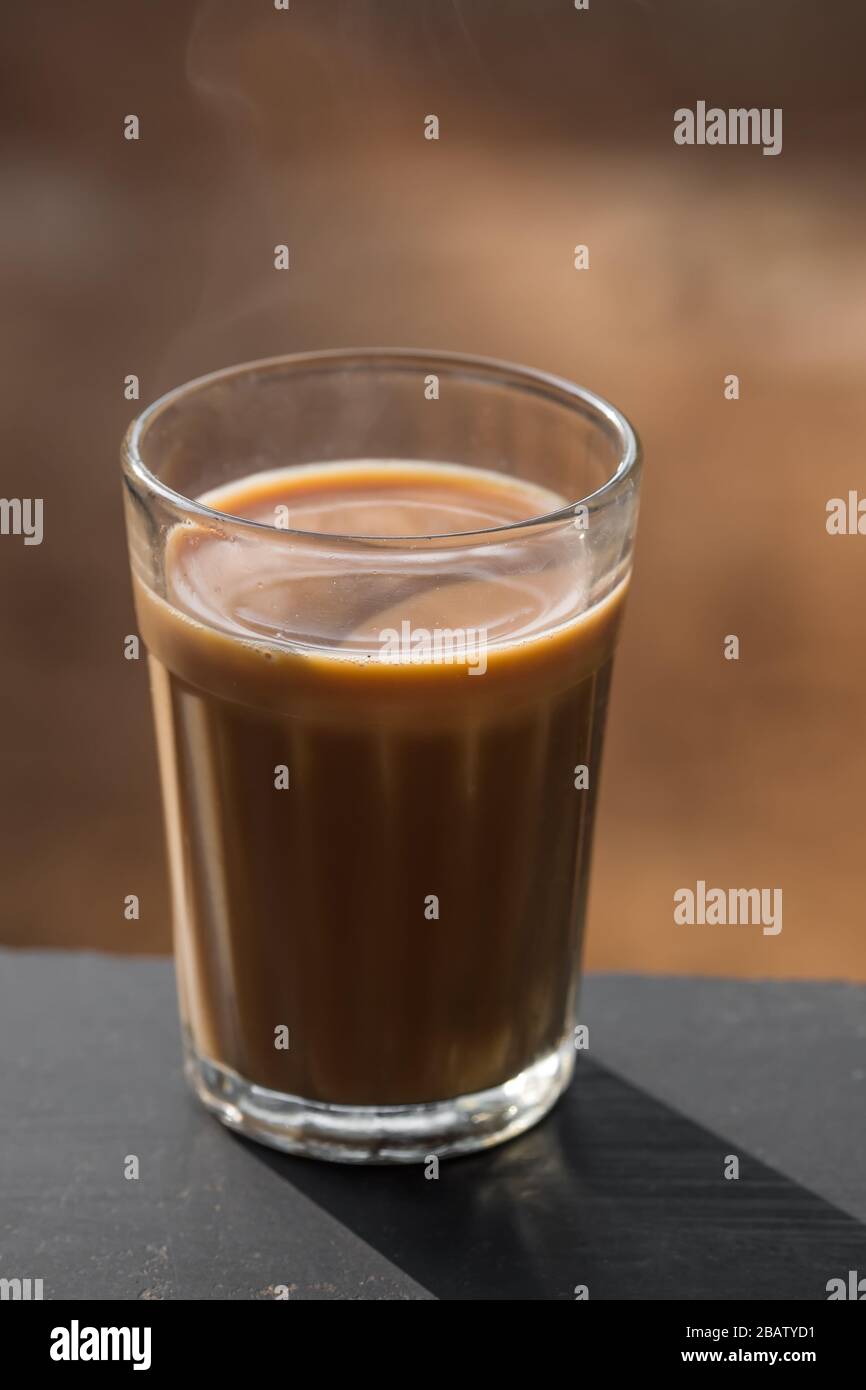 Thé masala indien en verre à facettes sur une planche en bois Banque D'Images