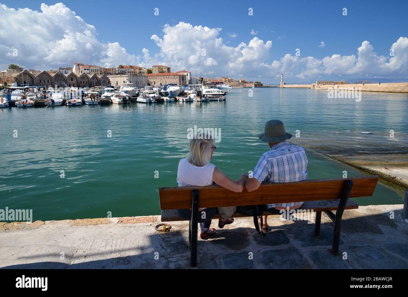 Couple de personnes âgées méconnaissables assis sur un banc et regardant la vue magnifique sur le port de la Canée sur l'île de Crète, Grèce. Banque D'Images