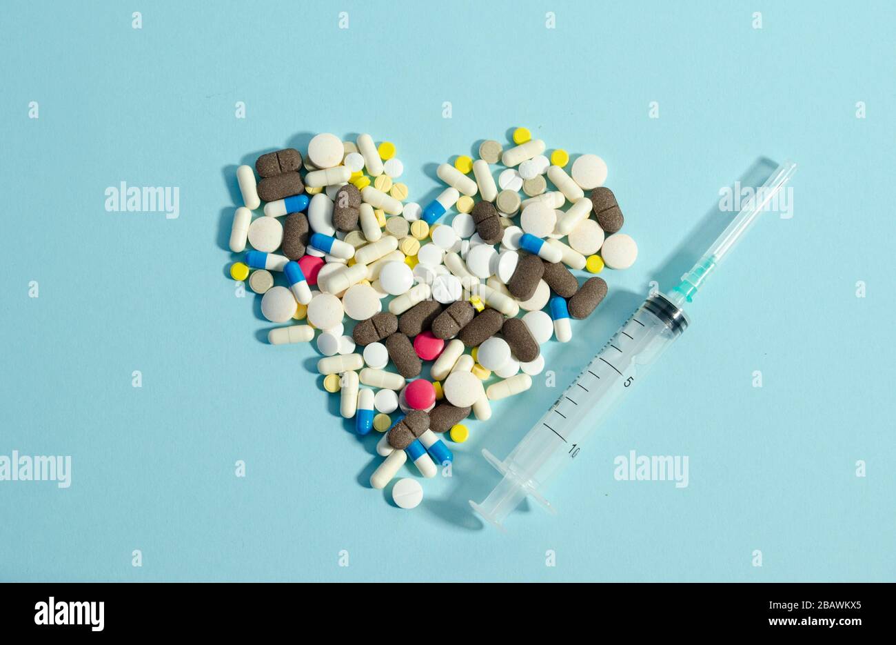Pilules se posant en forme de coeur sur fond bleu. Différentes pilules ensemble. Banque D'Images