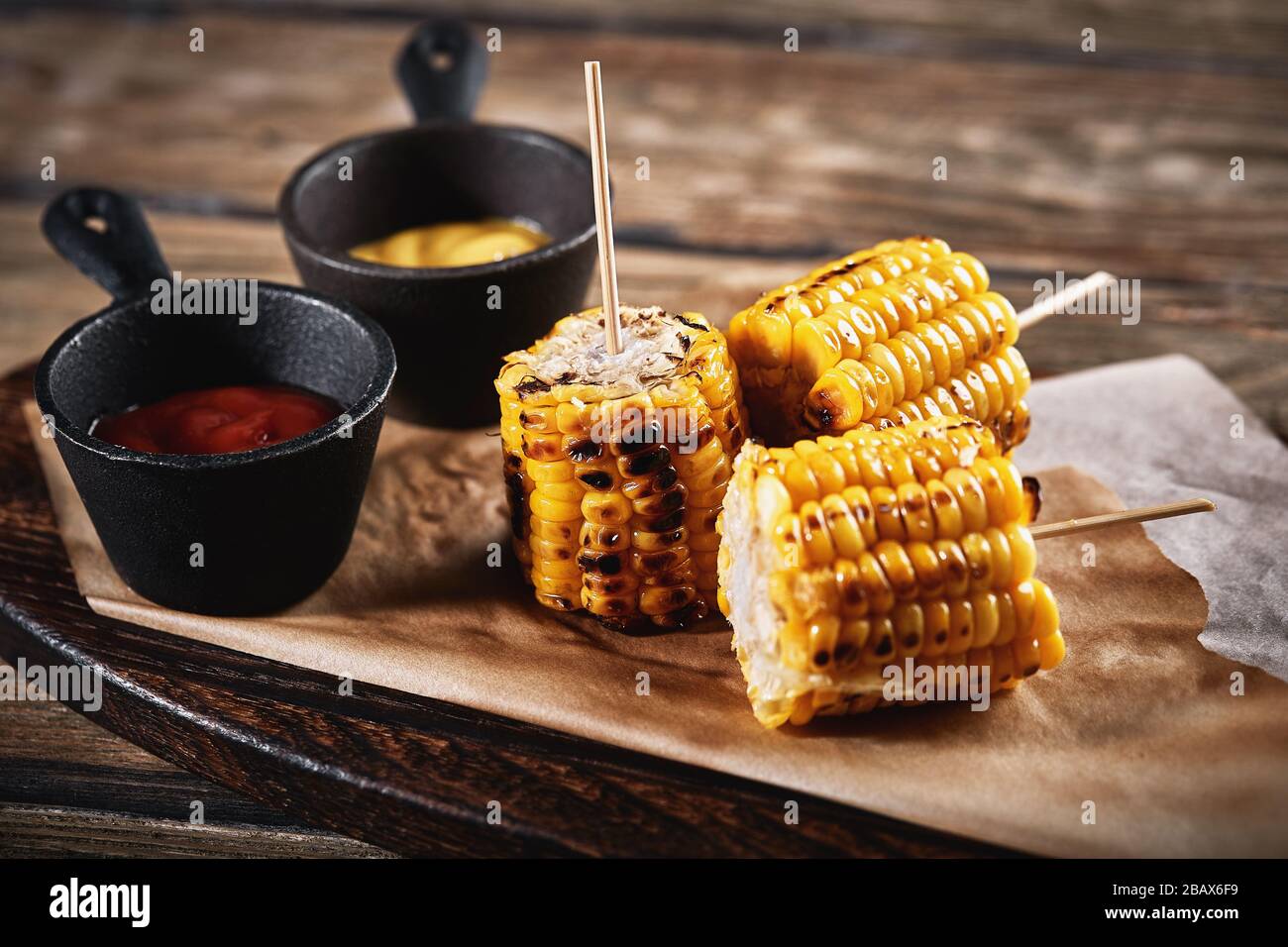 Maïs grillé avec sauces sur fond de bois. Accompagnement américain  traditionnel, arrière-plan sombre, espace de copie Photo Stock - Alamy