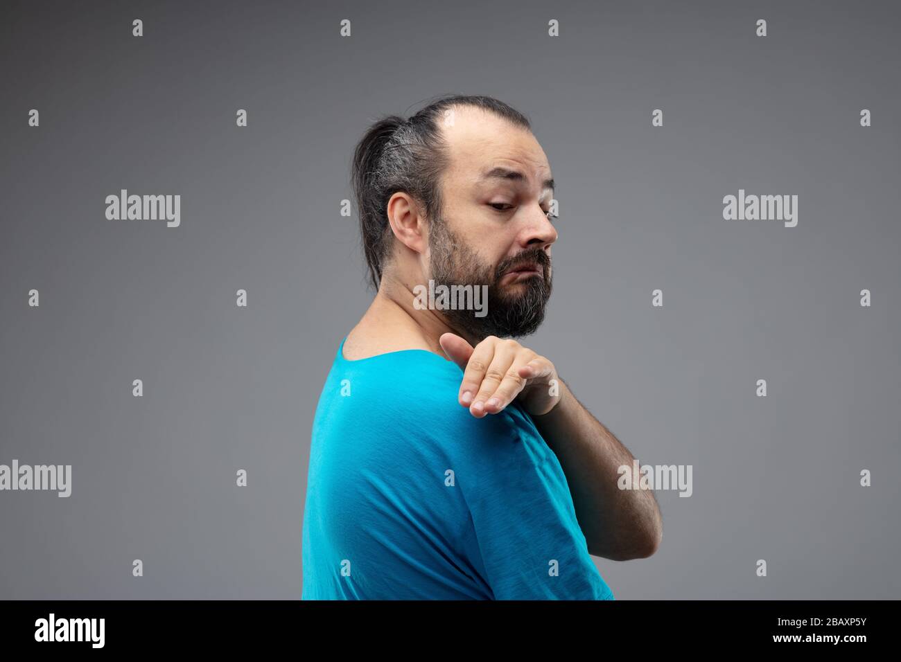 Homme barbu dans un t-shirt bleu montrant un geste méprisant avec ...