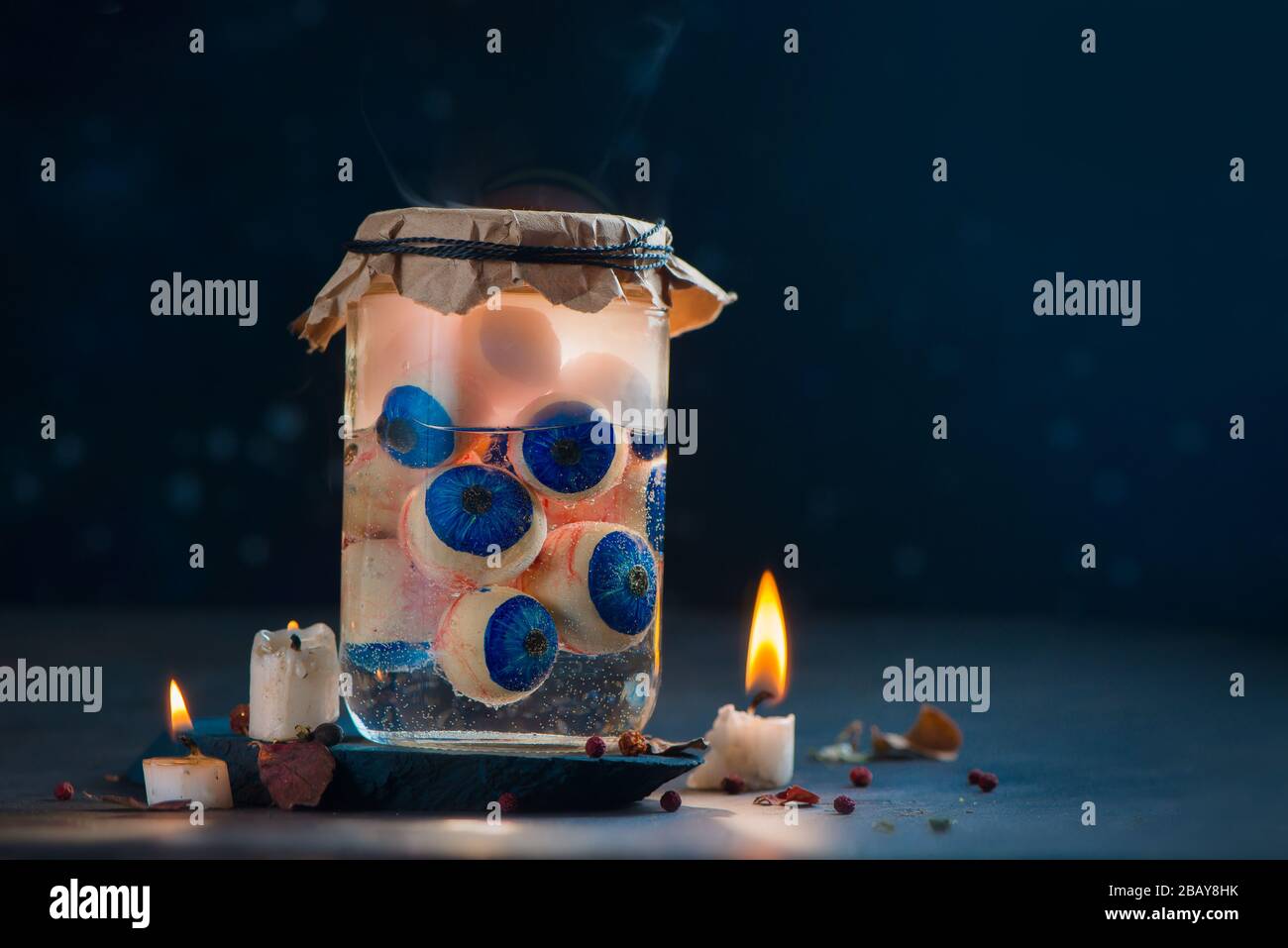 Bocal en verre avec boules à œil, tête d'Halloween éboueuse avec bougies Banque D'Images