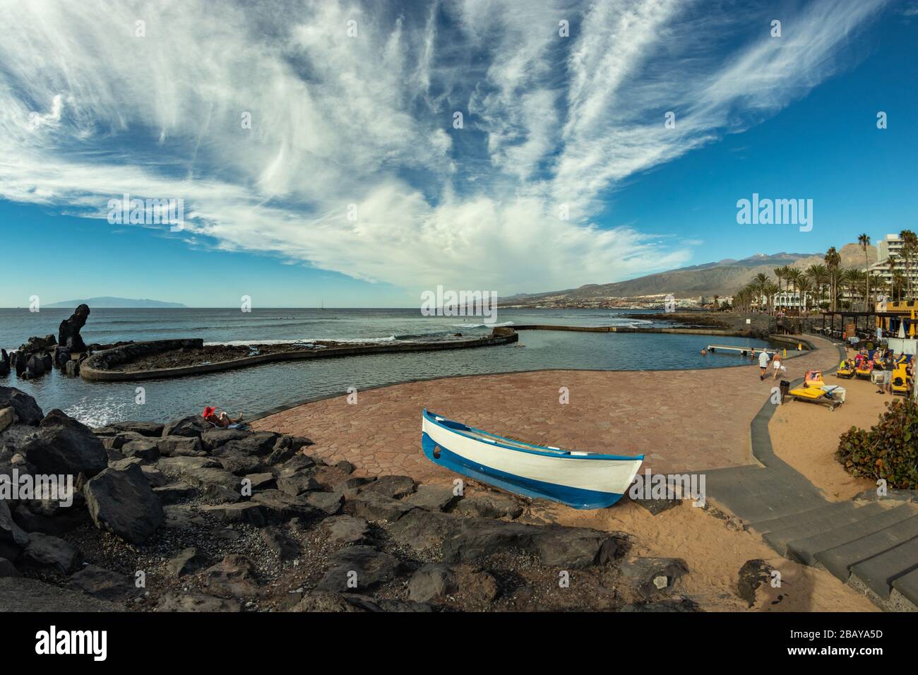 Côte à Las Americas, Tenerife, Espagne. Ciel bleu brillant avec de beaux nuages. Bateau de pêche au premier plan. Vue sur l'île de la Gomera. Banque D'Images