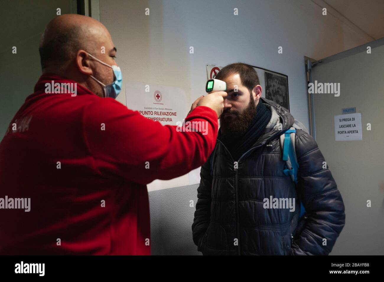 Milan, Italie. 27 mars 2020. Un membre de la Croix-Rouge contrôle la température corporelle d'un homme.en raison de l'urgence de Covid-19, l'unité de crise du Comité de la Croix-Rouge aide les citoyens qui ont besoin d'aide dans plusieurs municipalités, ils offrent des commissions comme l'alimentation et l'approvisionnement médical, les livraisons de repas préparés dans les hôpitaux, et services d'ambulance. Crédit: Valeria Ferraro/SOPA Images/ZUMA Wire/Alay Live News Banque D'Images