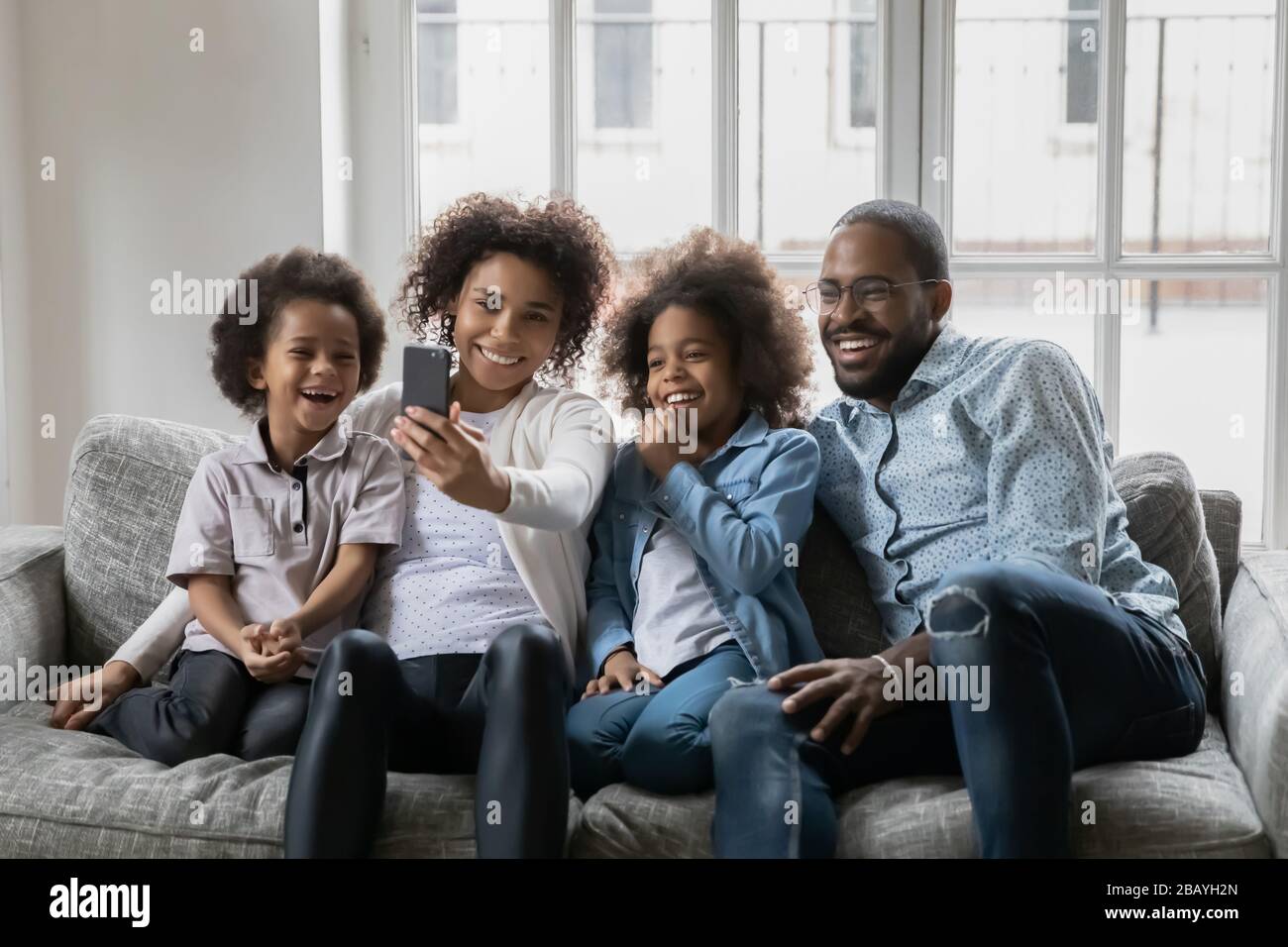Couple africain avec petits enfants qui font du selfie assis sur le canapé Banque D'Images